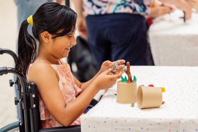 Girl in wheelchair playing with craft at a table