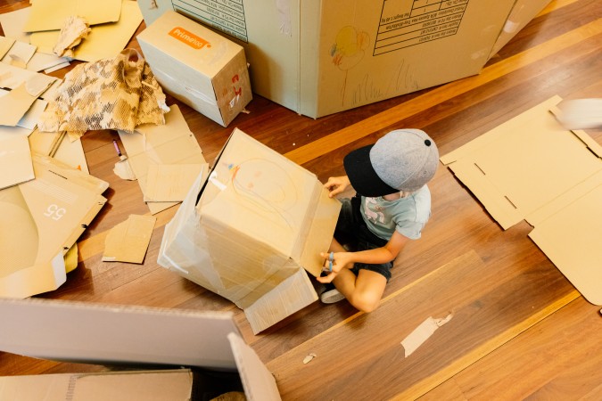 Boy sitting on floor playing with a cardboard box