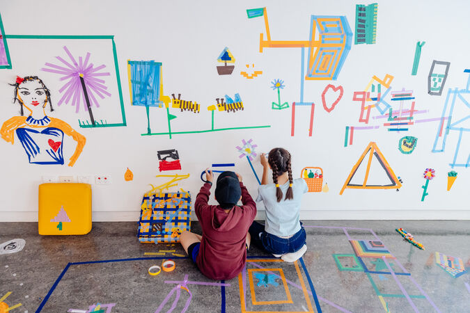 children drawing on wall with tape