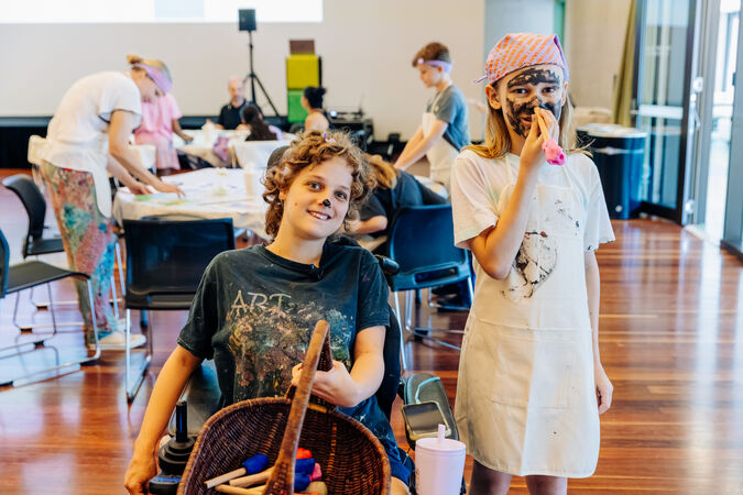 Girl in wheelchair and girl with painted face smiling