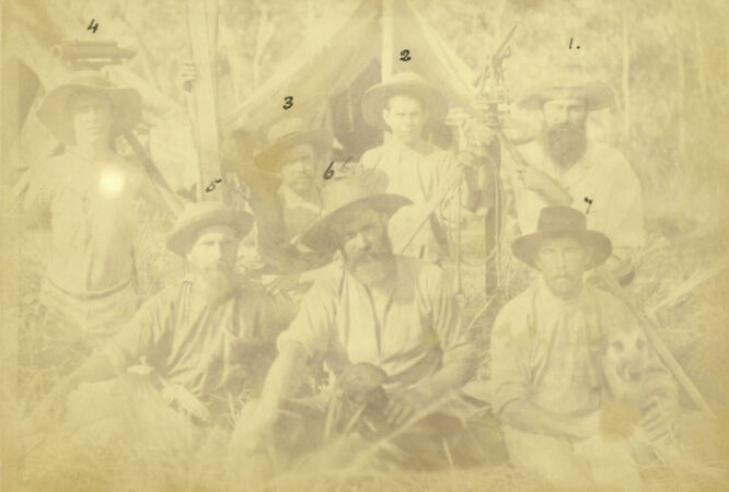 Group photograph of North Queensland survey staff men and their two dogs.