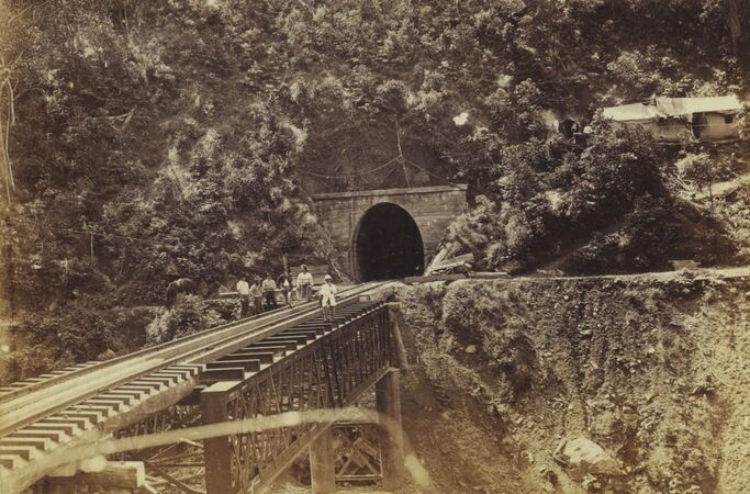 Men sitting on a railway bridge during construction, in front of Tunnel number 4 of the Cairns railway