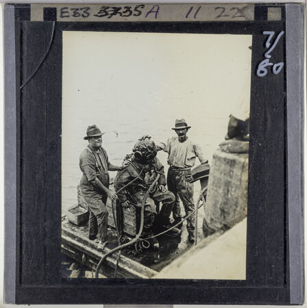 Two men assisting a diver on a wharf, Torres Strait Islands, Far North Queensland.