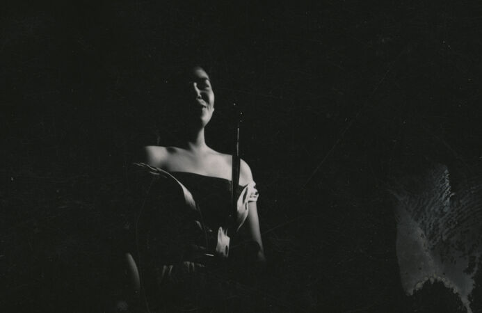 Moody black and white image of young singer in dimly lit room 