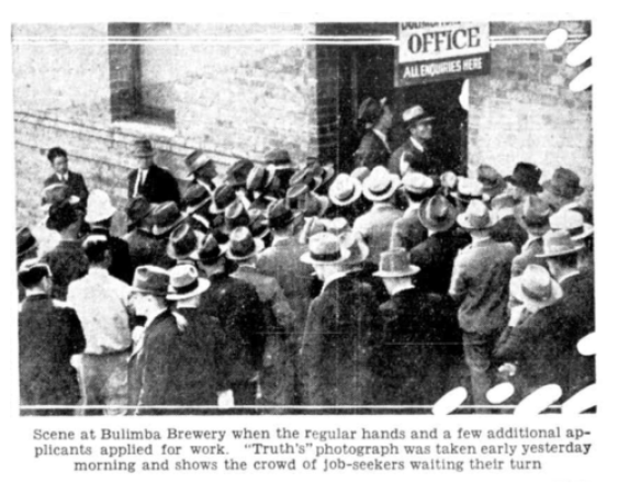 Black and white photograph of men milling together around and open office door.
