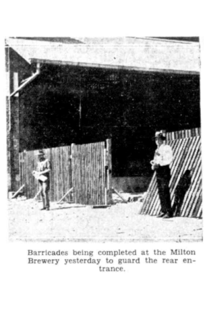 Black and white photograph of two men standing beside a partially-built high fence.