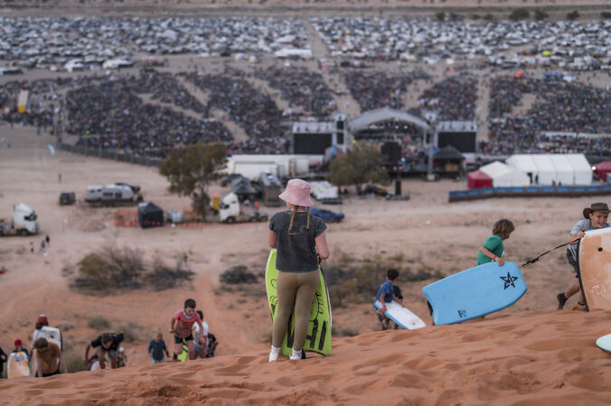 Chlildren with boards on sand dune overlooking Big Red Bash concert crowd
