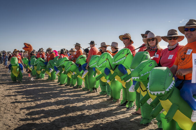 Row of people sitting on blow-up green dinosaurs