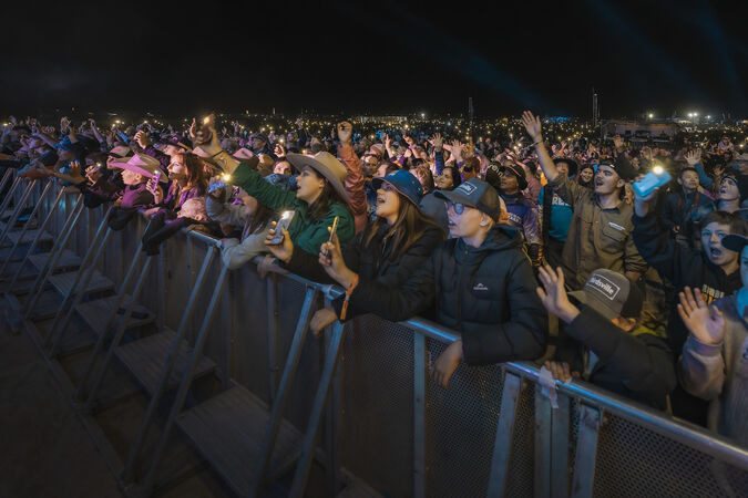 Concert crowd hanging over barricade