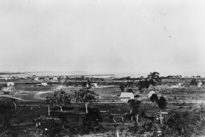 Black and white image of 1800s cottages with sea in background