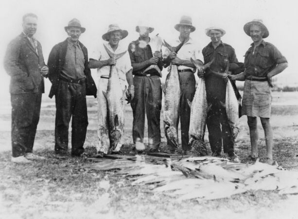 7 men from 1920s, holding catch of mackerel