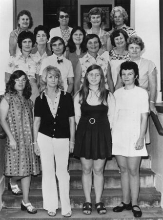 15 women in 1970s fashion standing on steps on building