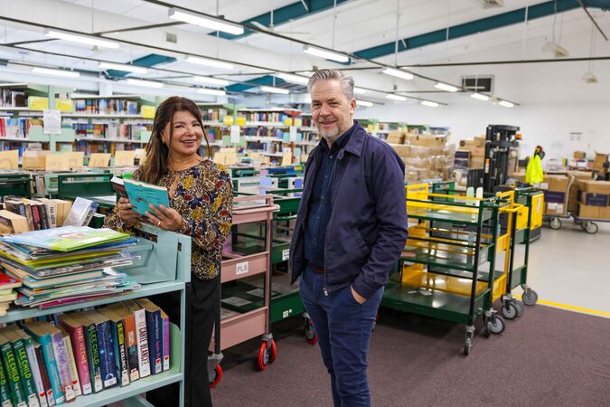 Woman and man standing among trolleys in library warehouse