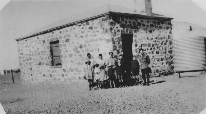 Teacher and students outside stone building in 1920s