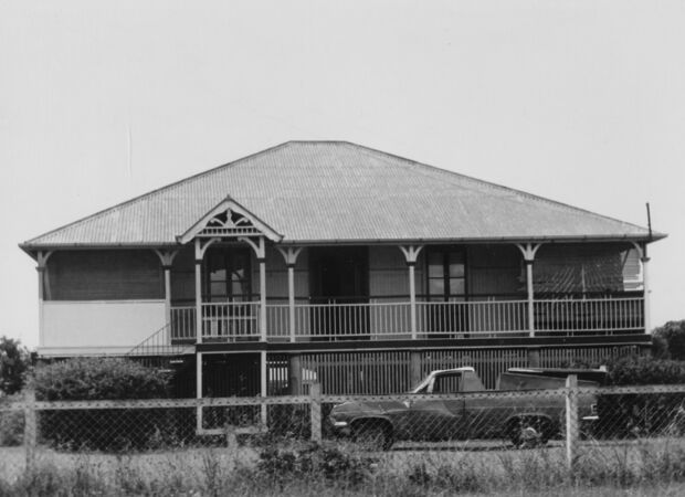 Black and white image of Queenslander home with ute parked out front