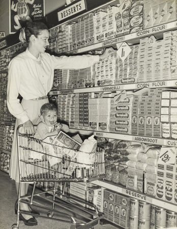 Woman with baby in shopping trolley at the Chermside Cash and Carry store, 1957
