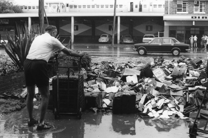 A staff member empties a wicker basket on a trolley that had been filled with flood damaged books and other debris from the State Library of Queensland building in South Brisbane