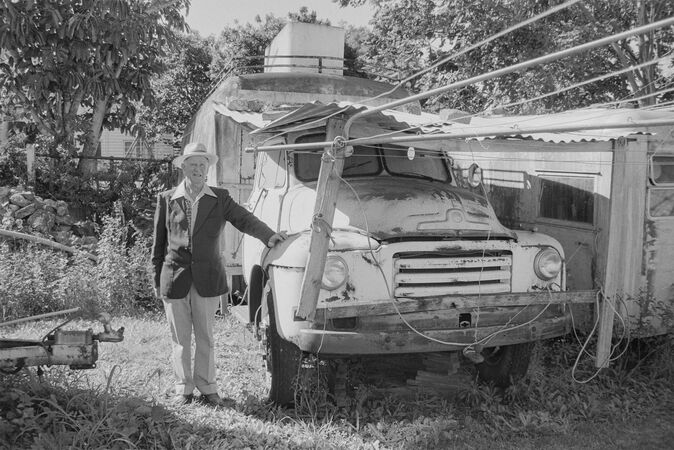 Man leaning on bonnet of old Bedford van next to backyard clothesline