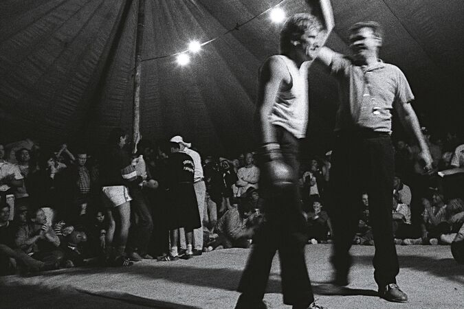 Man holding up boxer's arm in victory inside boxing tent