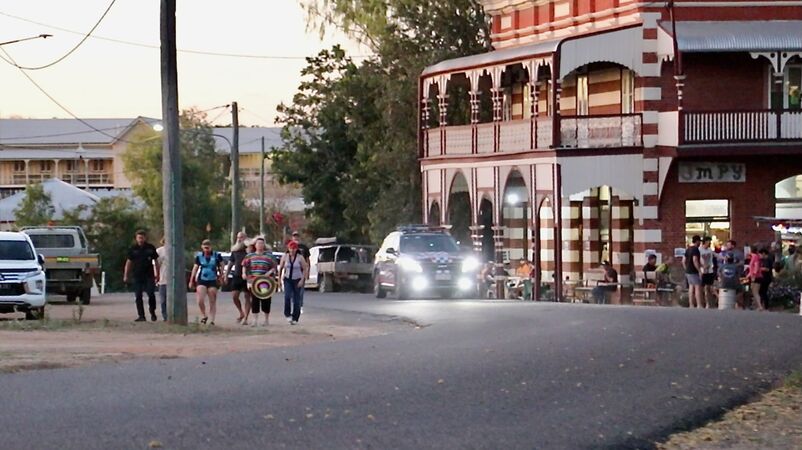 People walking along Macrossan St to attend the Halloween Ball in the area beside  the School of Arts. Imperial Hotel on right. 