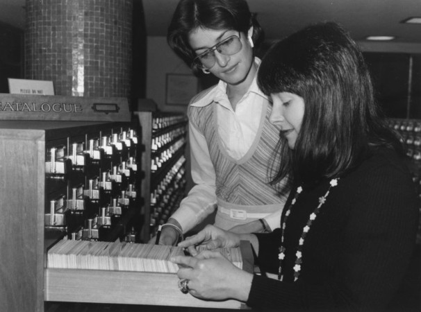 Black and white photograph of two women flicking through the card catalogue at the State Library