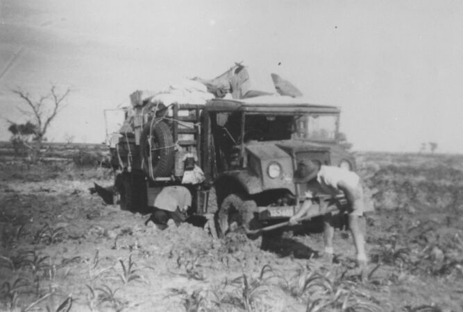 Man digging out bogged 1950s truck
