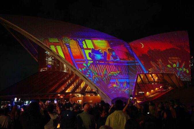 Sydney Opera House sails illuminated with a projection of a frog and girl on verandah of Queenslander