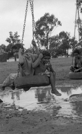 Boys playing on tire swings in a playground in Cherbourg