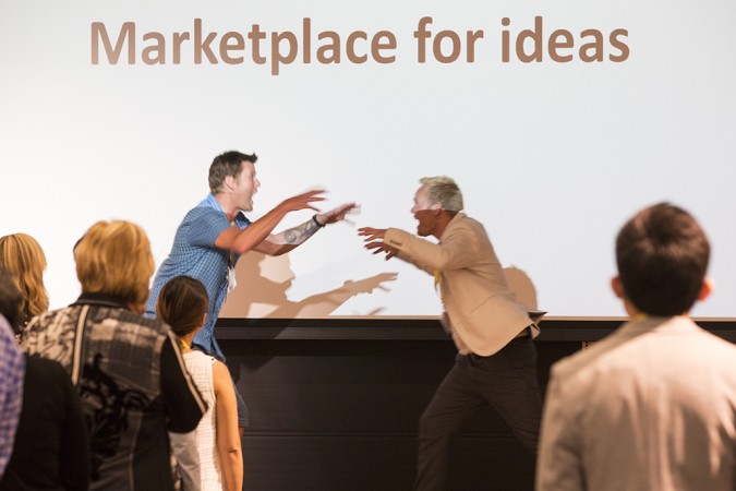Two men raise their arms excitedly during a presentation