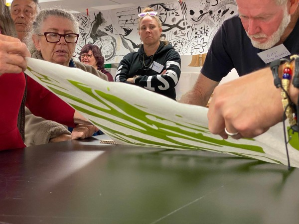 Participants, facilitators and volunteers learning from each other. Artsworker Gav Fenlon applies a sticker cut on the Fabrication Lab vinyl cutter. 