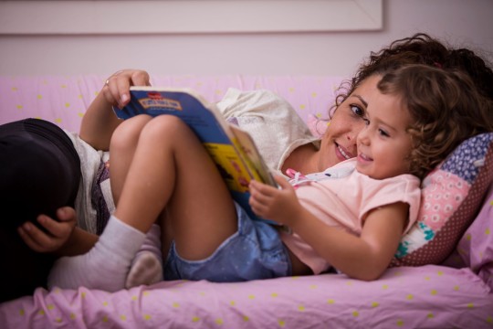 Woman and young girl lying down reading  