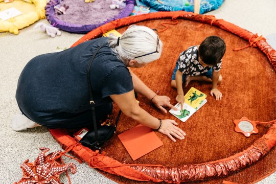 Caregiver and child reading a book about dinosaurs