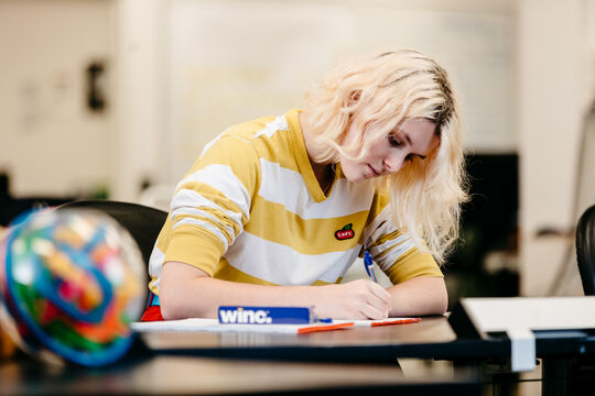A person writing on paper at a desk.