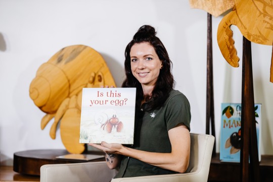 Illustrator, Emma Cracknell holds her picture book "Is this your egg?"
