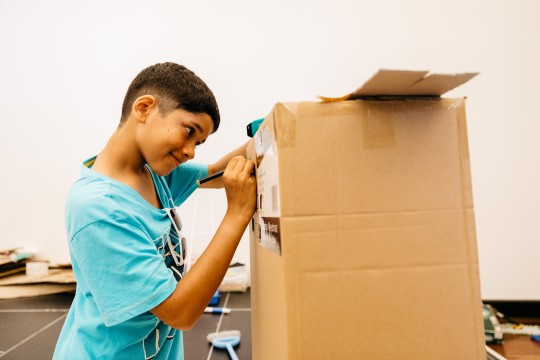 Young boy building cardboard creation