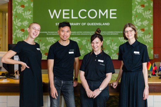 Four young staff members in front of a welcome sign