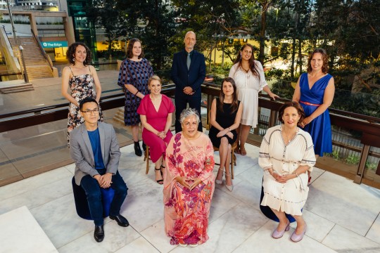 An elevated shot of ten winners of the Queensland Literary Awards seated and standing on the Queensland Terrace at State Library