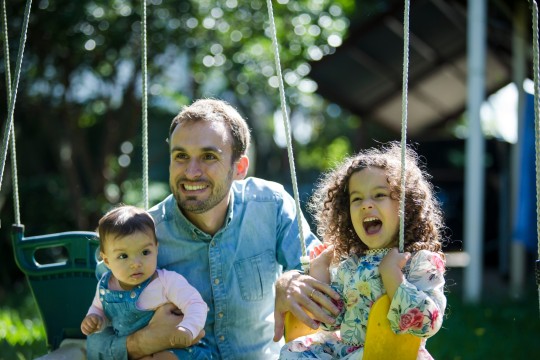Father with two children playing on the swing 2021 photography by Jason Henry First 5 Forever image library State Library of Queensland