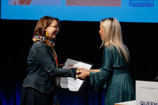 Woman accepting a framed award on stage.