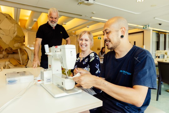 3 people use and learn to use a sewing machine