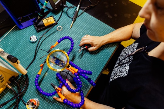 Someone soldering at an electronics bench 