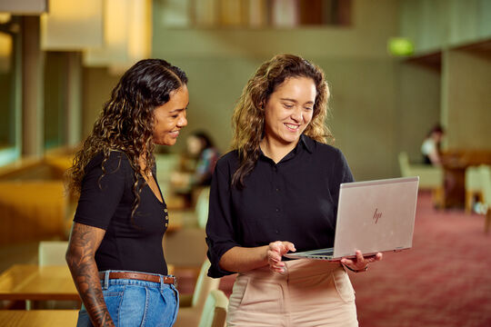 Two people smiling and looking at a laptop together.
