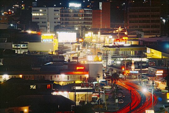 Aerial view of a Gold Coast street at nightime with neon lights, 1973