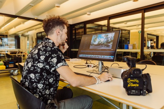 A photo of a man editing video footage on a computer screen