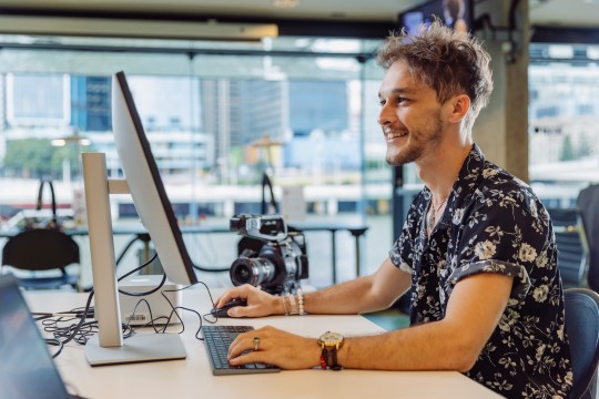 A young man working at a computer smiling