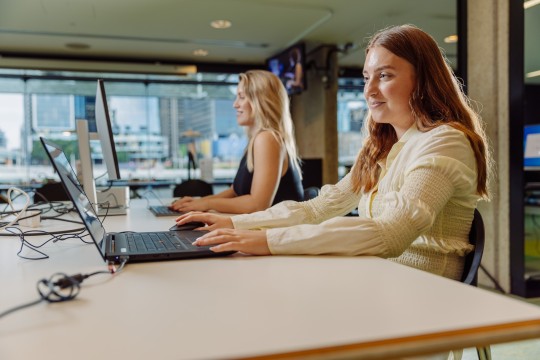 A photo of two young women using computers