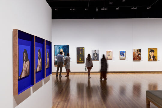 4 people admiring artworks within an exhibition.