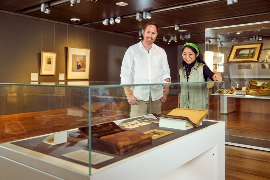 Two people looking at items in a glass case.