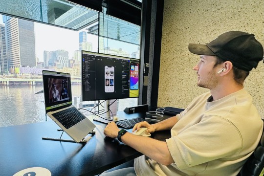 A photo of a man with a laptop and connected monitor