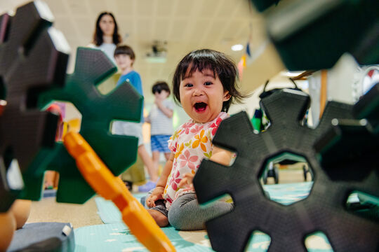 Toddler smiling as they play with construction cogs